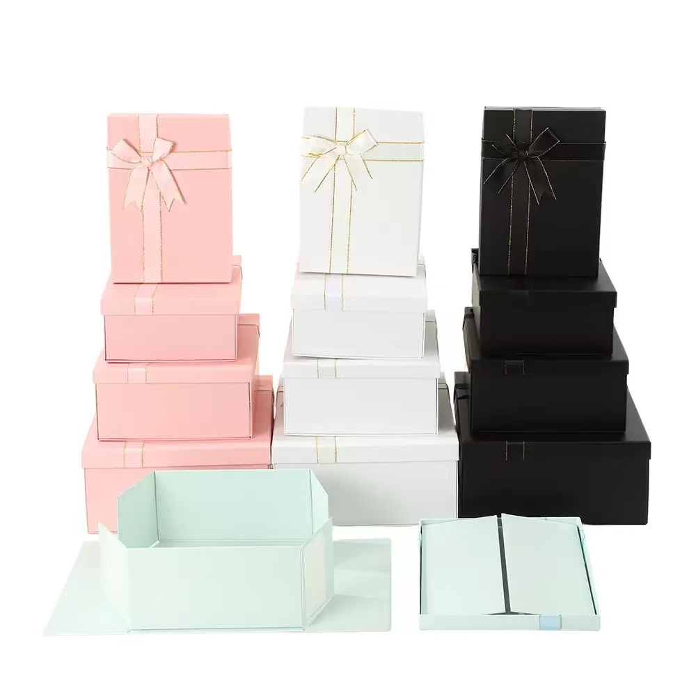 Stacked paper folding gift boxes​ with lids in pink, white, and black, showcasing various sizes and luxury ribbon designs. Ideal for custom packaging solutions.